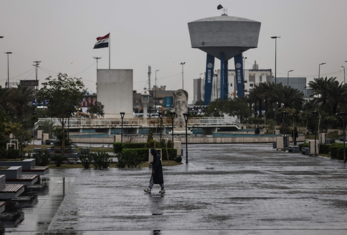 An Iraqi man walks through Al-Umma Park during rainfall in Baghdad on March 15, 2026. (Photo by AHMAD AL-RUBAYE / AFP)