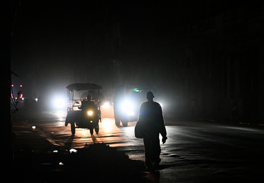 A man walks on a street without electricity during a nation wide blackout in Havana on March 21, 2026. (Photo by Yamil Lage / AFP)