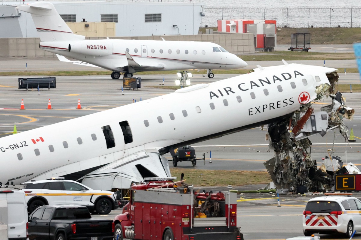 An executive jet taxis behind the Air Canada Express CRJ-900 that collided with a Port Authority fire truck at LaGuardia Airport in New York, after the airport resumed operations on March 23, 2026. Photo by TIMOTHY A. CLARY / AFP
