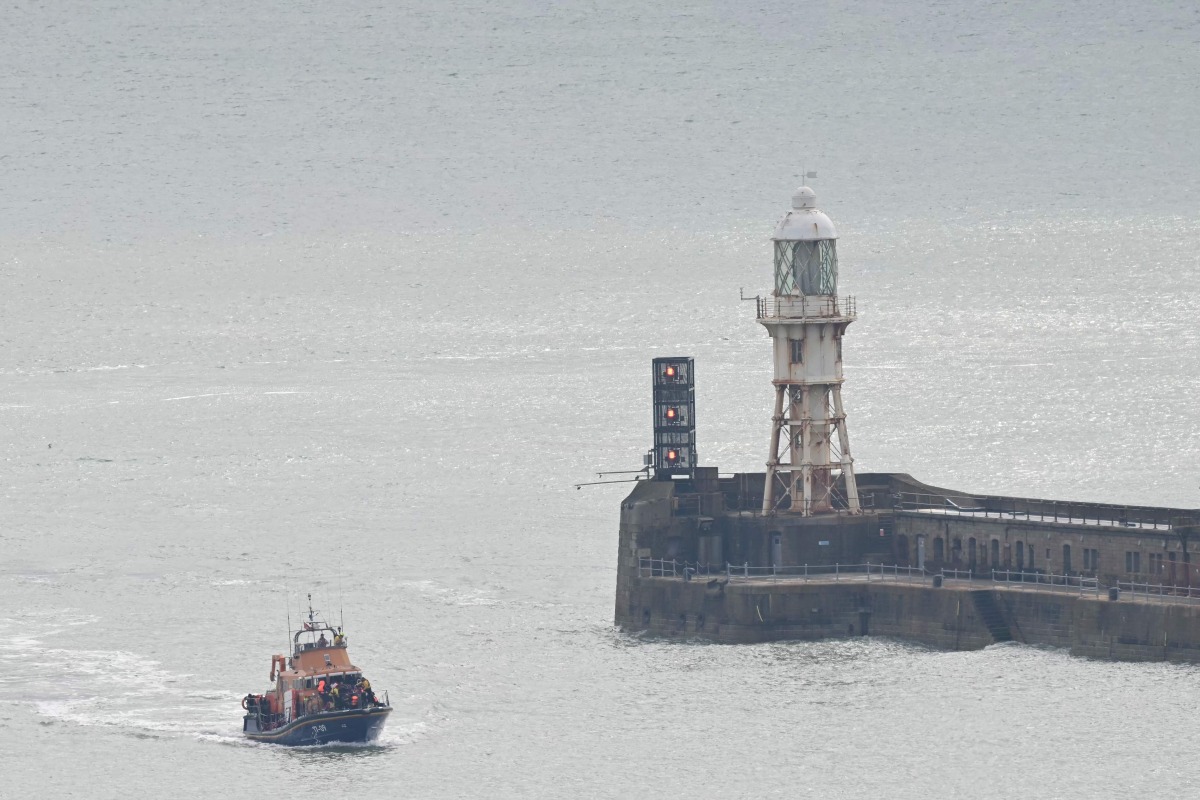 Migrants picked up at sea, while attempting to cross the English Channel from France, arrive into the Port of Dover in southeast England, on April 01, 2026 on board the Dover Royal National Lifeboat Institution lifeboat. (Photo by JUSTIN TALLIS / AFP)