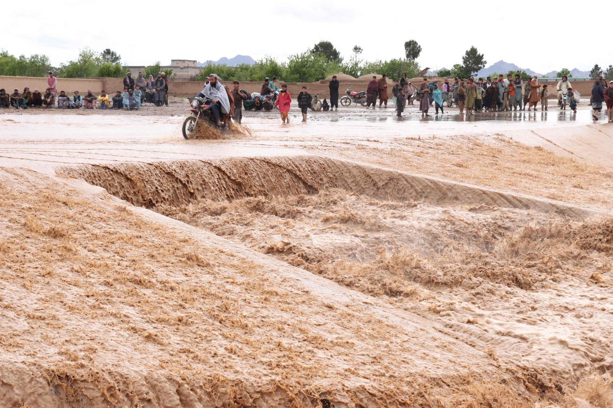 An Afghan motorist wades across a flooded road at Zawul district in Herat province on April 2, 2026. (Photo by Mohsen KARIMI / AFP)