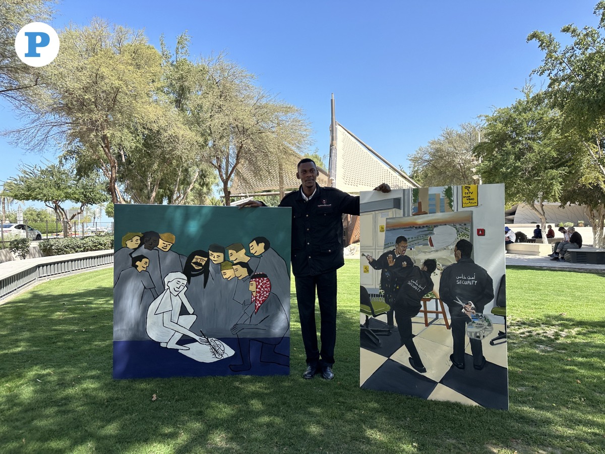 Security officer at the National Museum of Qatar, AbduRahman Hussein Khamis holding some of his paintings. Photo by Alexandra Evangelista /The Peninsula