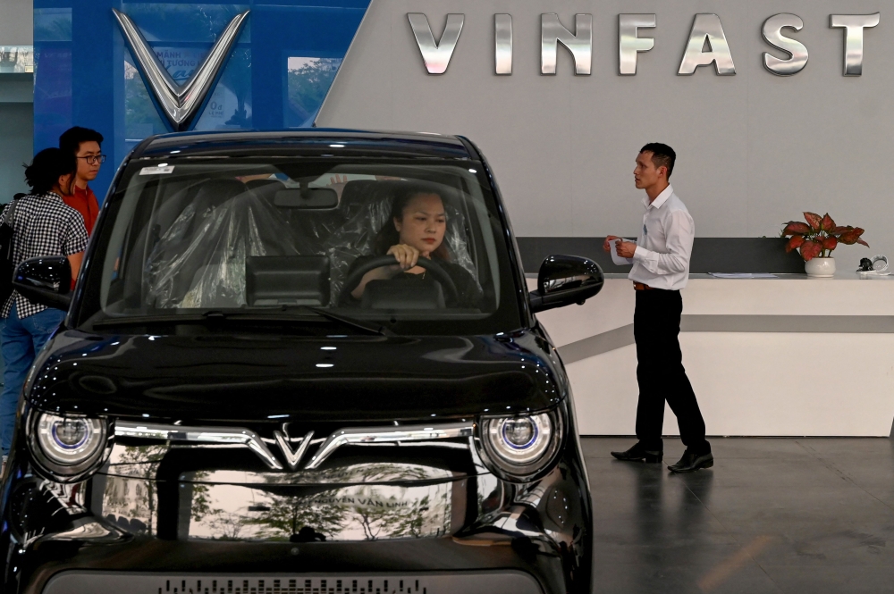This photo taken on April 11, 2026, shows a woman behind the wheel of a car inside a Vinfast electric car dealership in Hanoi. (Photo by Nhac Nguyen / AFP)