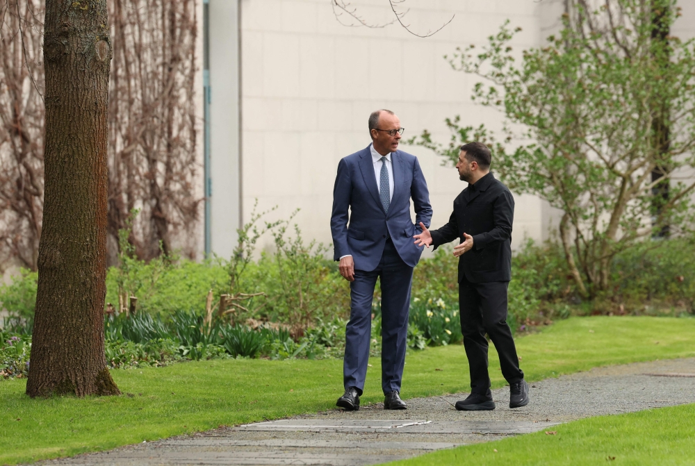 German Chancellor Friedrich Merz and Ukrainian President Volodymyr Zelensky walk in the garden in the backyard of the Chancellery in Berlin on April 14, 2026 (Photo by Odd Andersen/ AFP) 