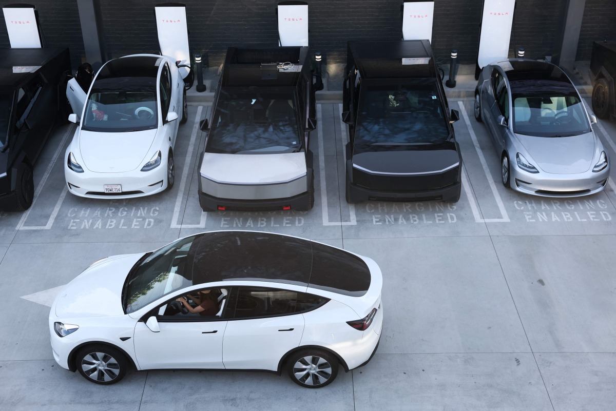 Tesla electric vehicles, including the Cybertruck, charge at stations during the opening of the Tesla Diner and Drive-In restaurant and Supercharger on Santa Monica Blvd in the Hollywood neighborhood Los Angeles, California on July 21, 2025. Photo by Patrick T. Fallon / AFP