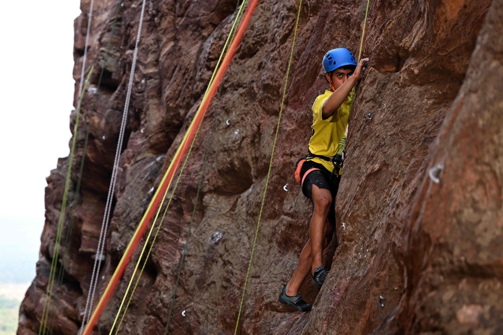 This photograph taken on March 28, 2026 shows a climber scaling a rock wall during a rock climbing festival at a sandstone cliffs site in Karnataka's Badami town. (Photo by Sajjad Hussain / AFP)