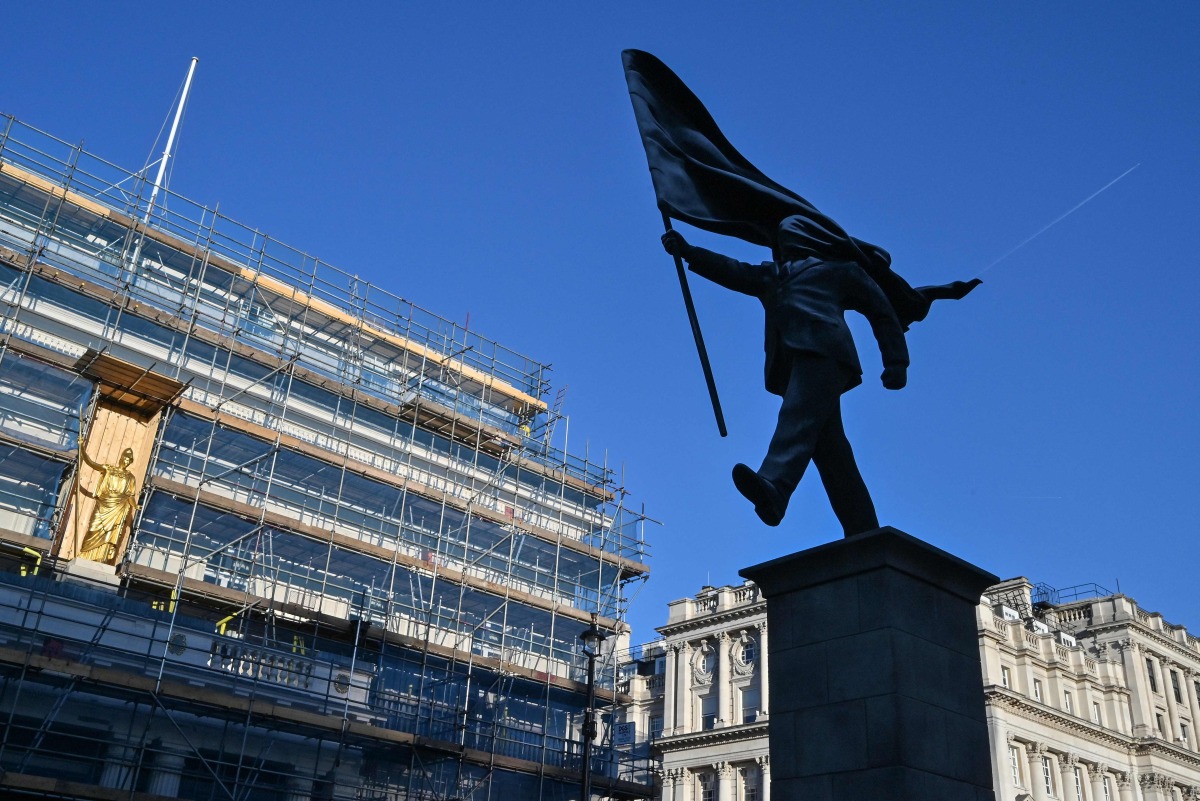 A statue (R) which suddenly appeared the day before, bearing the signature of British street artist Banksy etched onto its base, is pictured in Waterloo Place in central London early morning on April 30, 2026. Photo by Richard A. Brooks / AFP