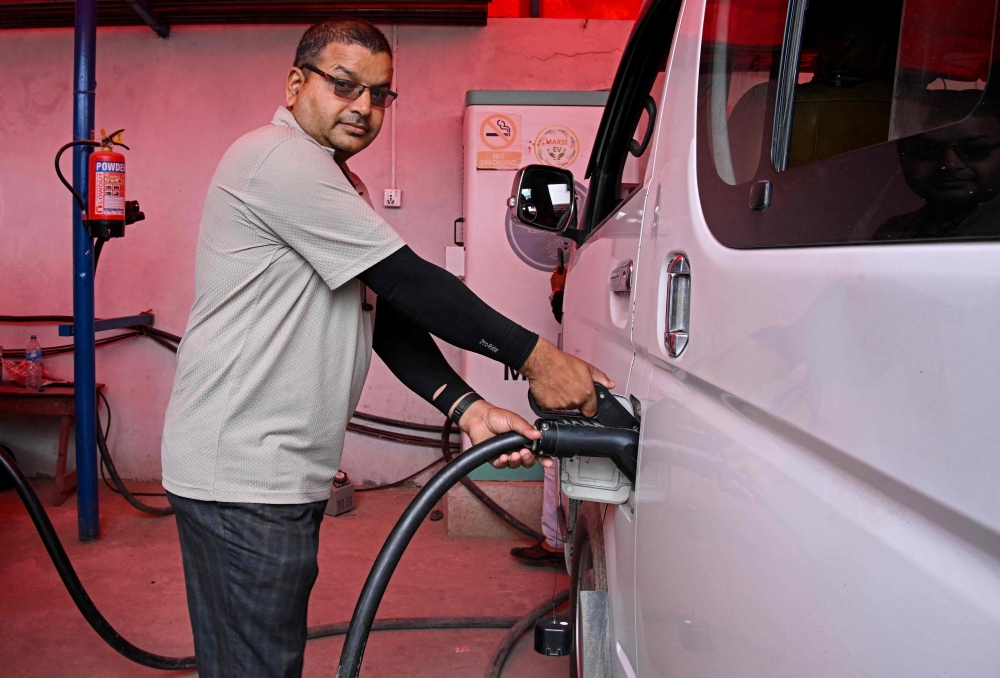 NEPAL-TRANSPORT-AUTOMOBILE-ENERGY
Electric microbus driver Purushottam Adhikari charges his vehicle at a charging station in Kathmandu on May 1, 2026. As global fuel markets reel from the Middle East war, motorists in Nepal are increasingly turning to electric vehicles, with high demand putting a strain on dealerships. 
(Photo by Prakash MATHEMA / AFP) / TO GO WITH 'Nepal-Transport-Automobile-Energy' FOCUS