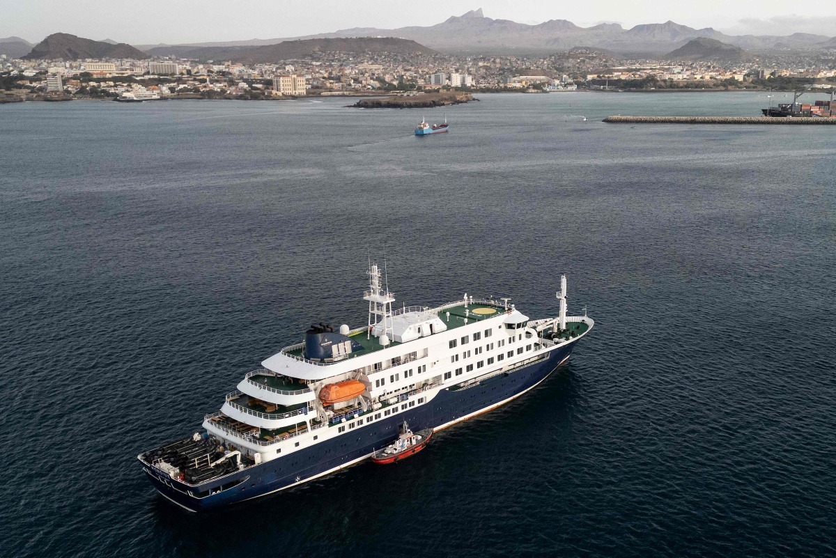 This aerial view shows health personnel boarding the cruise ship MV Hondius, while stationary off the port of Praia, the capital of Cape Verde, on May 6, 2026. Photo by AFP