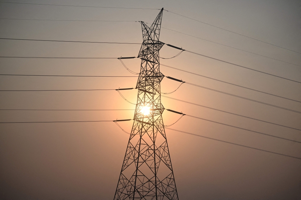 (Files) This file photo taken on April 16, 2026 shows the sun setting next to power lines along San Fernando town, Pampanga province, north of Manila. (Photo by Ted Aljibe / AFP)