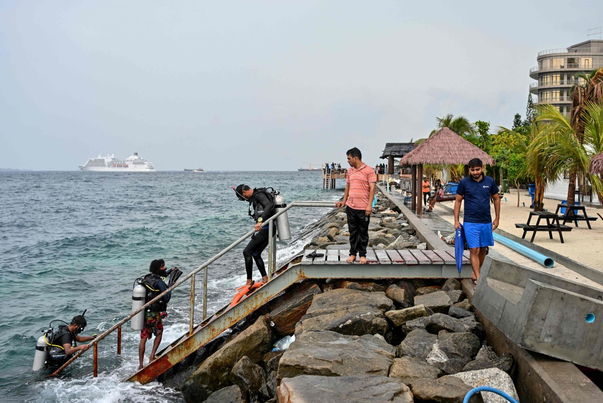 A tourist, along with guides, returns after an open-water diving session near Rasfannu Beach in Malé on May 15, 2026. Photo by Mohamed Afrah / AFP
