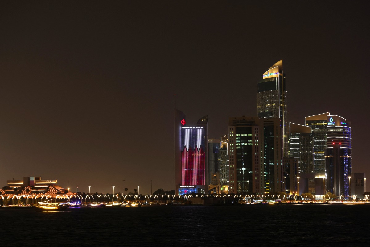 Illuminated skyscrapers are pictured along the corniche promenade in Doha on May 15, 2026. Photo by Karim JAAFAR / AFP