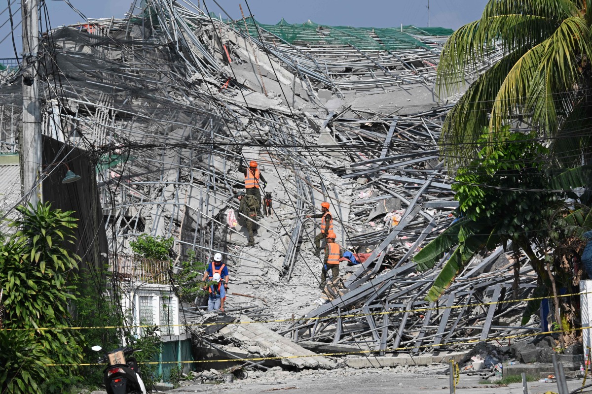 Military personnel with a working dog conduct search and rescue operations at a collapsed building in Angeles City, Pampanga province, north of Manila on May 25, 2026. Photo by Ted ALJIBE / AFP