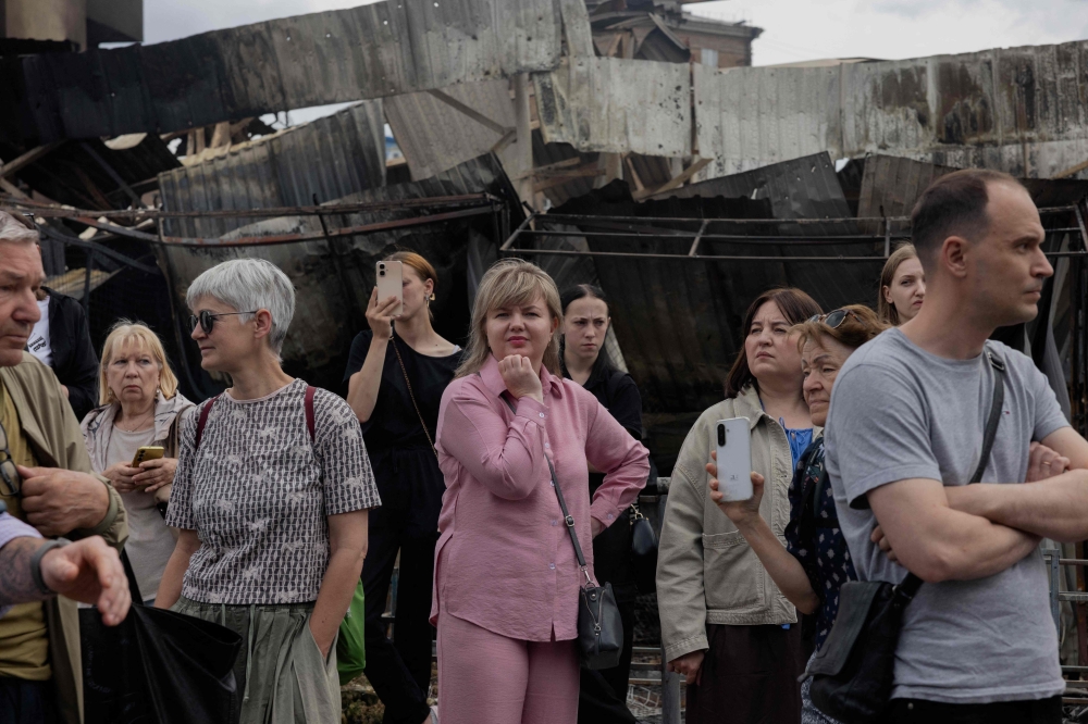 Local residents stand by a damaged shopping center following Russian strikes in Kyiv on May 25, 2026. (Photo by Tetiana Dzhafarova / AFP)