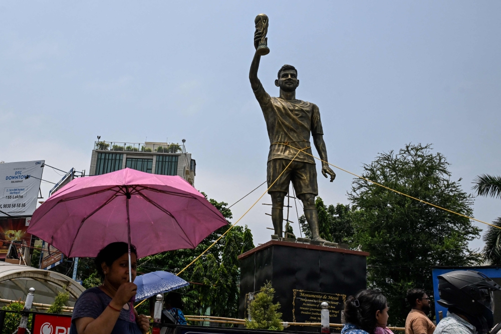 Commuters walk past a statue of Argentine football player Lionel Messi in Kolkata on May 27, 2026. (Photo by Dibyangshu Sarkar / AFP)