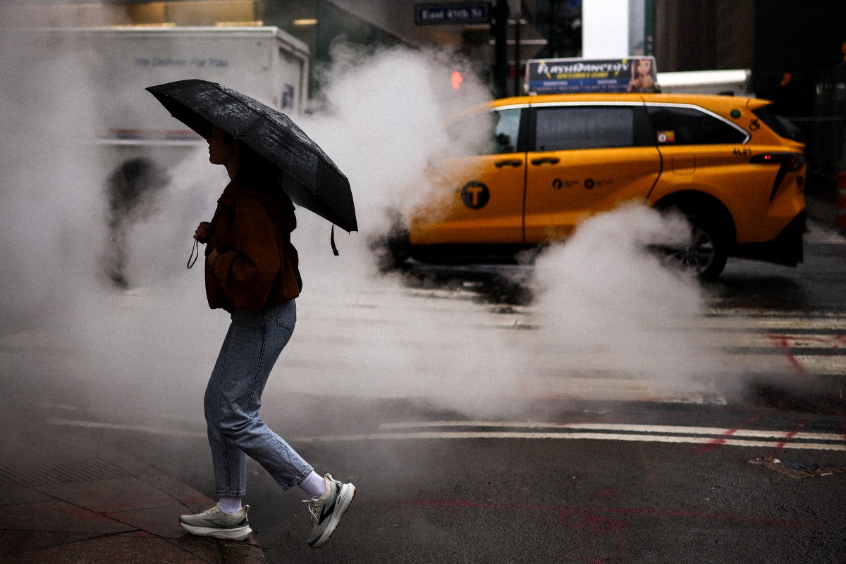 A woman holding an umbrella crosses the street in the rain in New York City, on May 24, 2026. Photo by CHARLY TRIBALLEAU / AFP