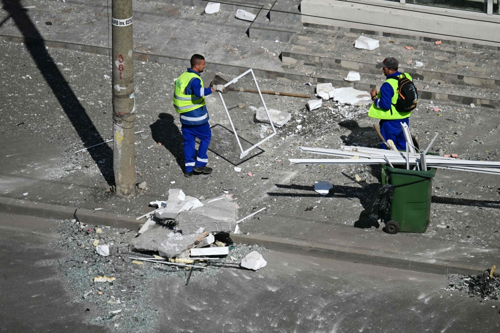 Municipal workers clear debris from the street after a Russian drone struck an apartment building in Galati, western Romania. (Photo by Daniel Mihailescu / AFP)
 