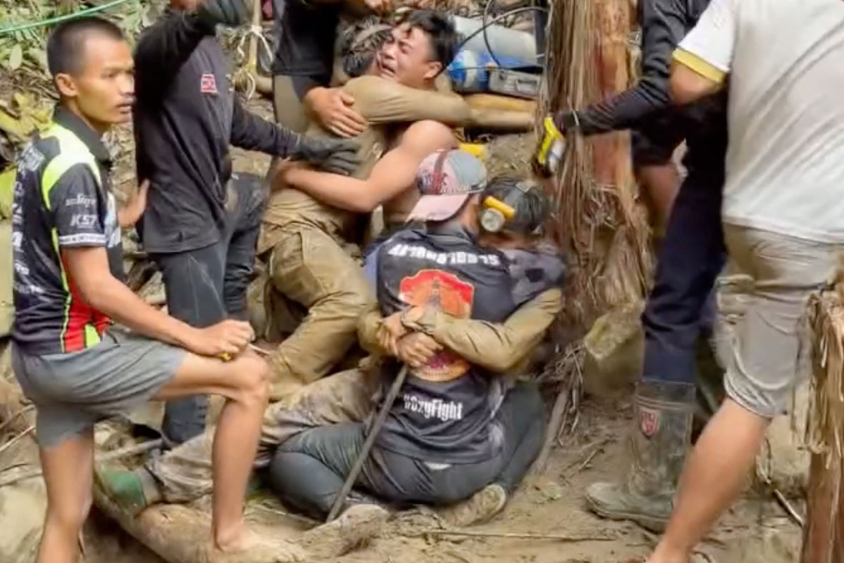 This screen grab made from handout video footage taken on May 30, 2026, and provided by Adisak Wongsoraya, shows two men (centre L and centre R, with headlamp) being hugged after they were rescued from a semi-submerged cave in Laos' central Xaysomboun province, northeast of the capital Vientiane. Photo by Handout / Adisak Wongsoraya / AFP