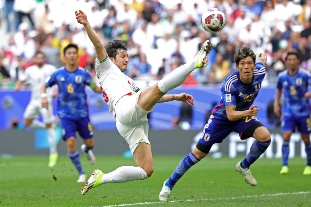(FILES) Iran's forward #20 Sardar Azmoun shoots the ball past Japan's defender #22 Takehiro Tomiyasu during the Qatar 2023 AFC Asian Cup quarter-final football match between Iran and Japan at Education City Stadium in al-Rayyan, west of Doha, on February 3, 2024. (Photo by Giuseppe Cacace / AFP)