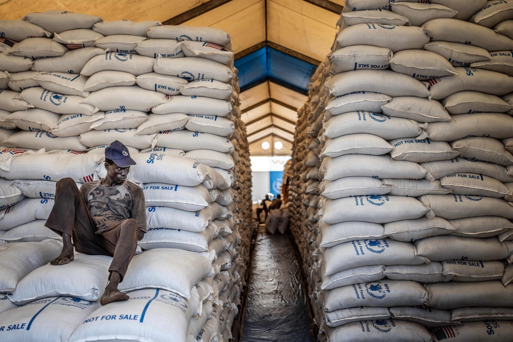 (Files) A worker sits atop sacks of food aid in a hangar at a World Food Programme (WFP) warehouse in Bor, Jonglei State, on February 13, 2026. (Photo by Luis Tato / AFP)
 