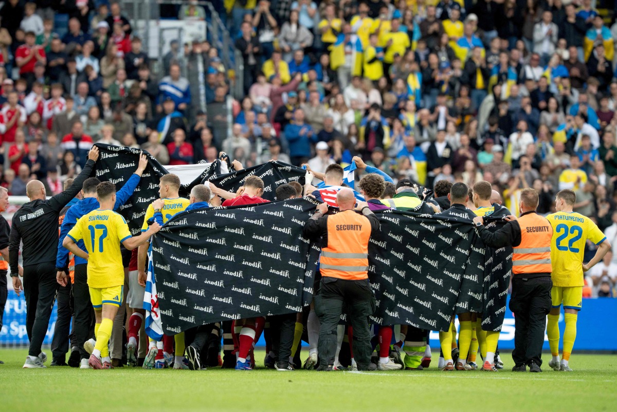 Denmark's and Ukraine's players huddle to accompany Christian Eriksen to a waiting ambulance during the football international friendly match between Denmark and Ukraine at Odense Stadium in Denmark, on June 7, 2026.  (Photo by Bo Amstrup / Ritzau Scanpix / AFP) / Denmark OUT