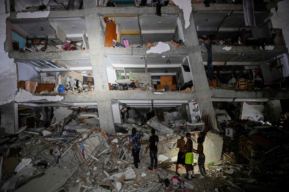 People stand in the rubble near a damaged building following an earthquake in Catia La Mar, La Guaira State, some 30kms north-west of Caracas, early on June 25, 2026. (Photo by Federico Parra/ AFP)