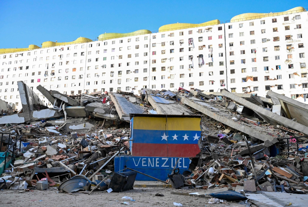 A Venezuelan flag is seen painted on a damaged wall amid the rubble of a collapsed building following earthquakes in Caraballeda, La Guaira state, Venezuela, on June 26, 2026. (Photo by Maryorin Mendez / AFP)