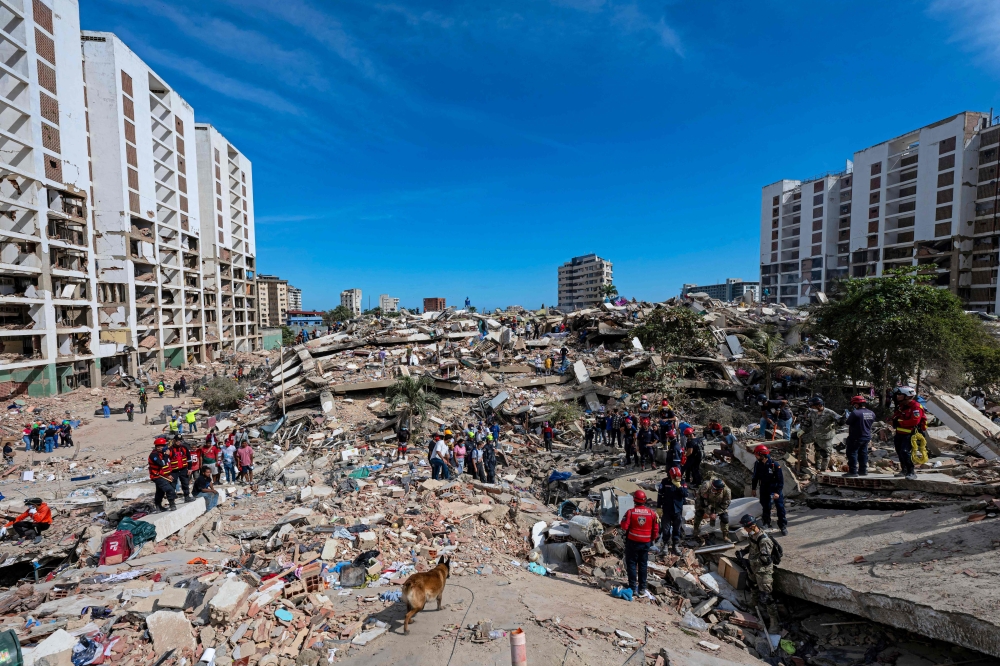 A rescue dog from the Argentine search and rescue team searches for bodies in the rubble of a collapsed building in Caraballeda, La Guaira state, Venezuela, on June 28, 2026, following twin earthquakes. (Photo by Miguel Medina / Pool / AFP)