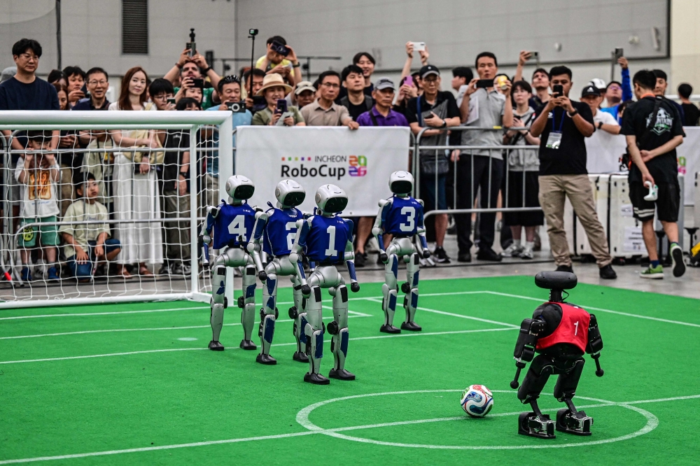 Spectators watch robots taking part in a football match at RoboCup 2026, a robotics and Artificial Intelligence (AI) competition in Incheon on July 3, 2026. (Photo by Jade Gao / AFP)