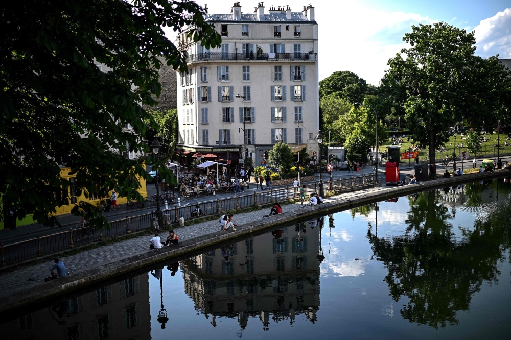 Files: People sit along the canal Saint-Martin in Paris on May 17, 2022. Photo by Christophe Archambault / AFP