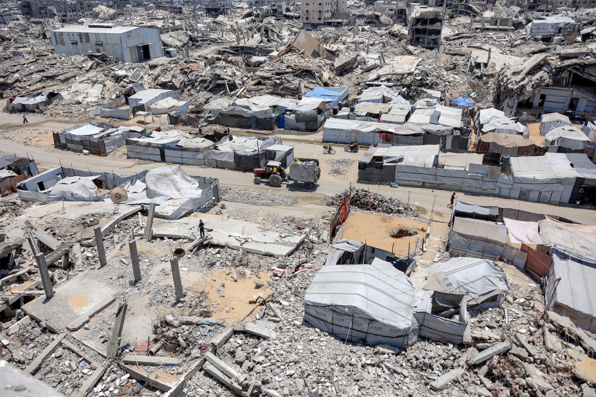 Tents and shelters are pictured next to rubble of collapsed buildings at a camp for people displaced by war in the Sheikh Radwan neighbourhood of Gaza City on July 6, 2026. Photo by OMAR AL-QATTAA / AFP