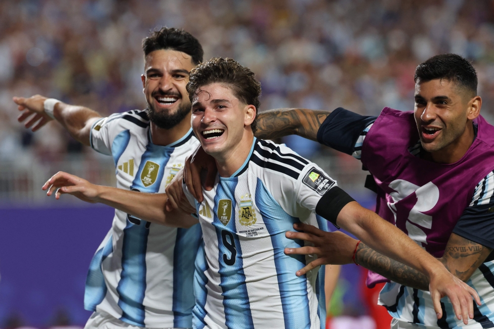 Argentina's forward #09 Julian Alvarez (C) celebrates scoring his team's second goal with Argentina's forward #21 Jose Manuel Lopez (L) and Argentina's defender #13 Cristian Romero. Photo by Odd Andersen / AFP