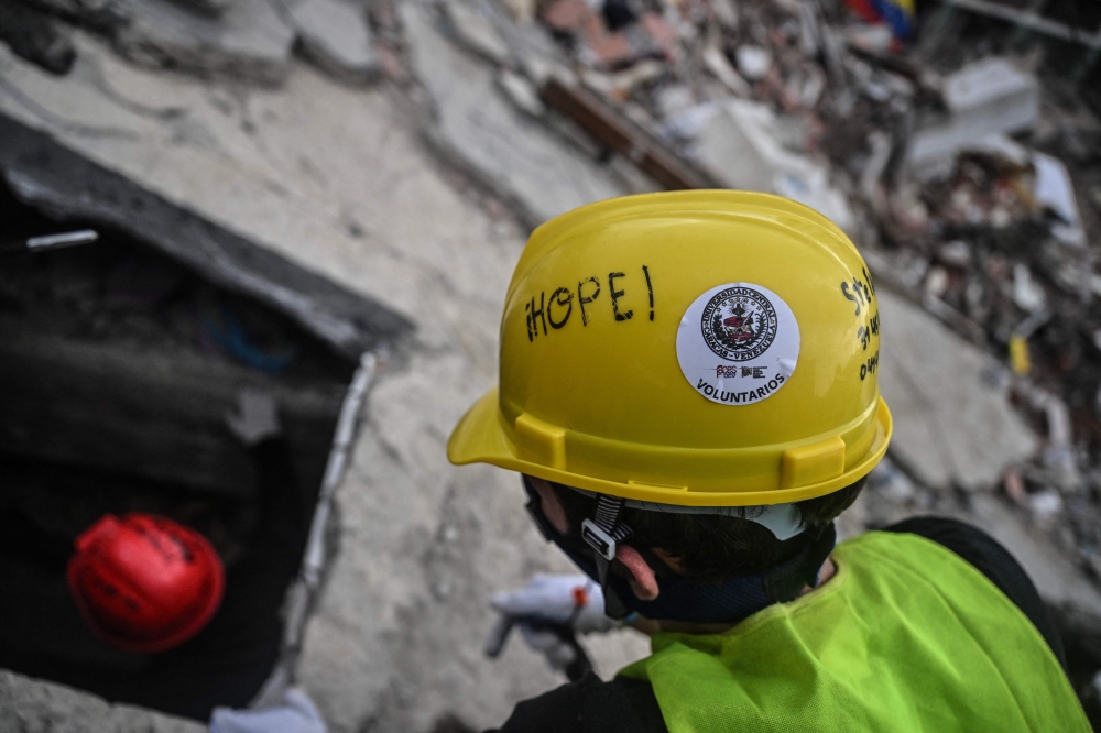 Volunteers and Mexican rescuers search for bodies amid debris of buildings damaged by the June 24 earthquakes, in Tanaguarena, state of La Guaira; Venezuela, on July 18, 2026. (Photo by Juan Barreto / AFP)