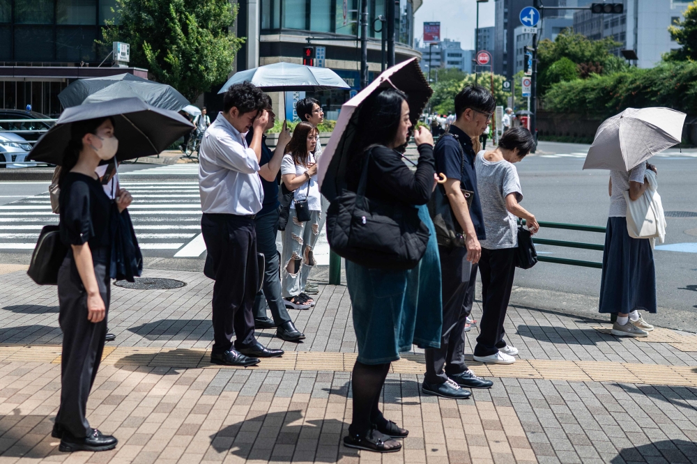 People carry umbrellas to shelter from the sun in Tokyo on July 23, 2026. (Photo by Andrew Caballero-Reynolds/ AFP)
 