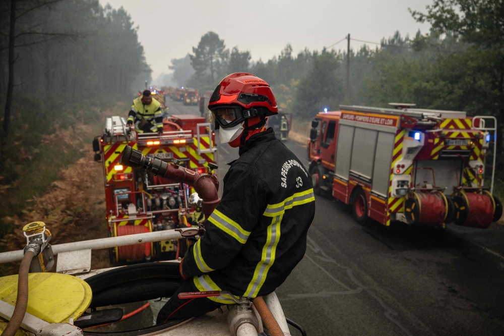 Firefighters operate from a column of firefighters vehicles near the town of Lacanau, in southwestern France on July 25, 2026. (Photo by Julien De Rosa / AFP)