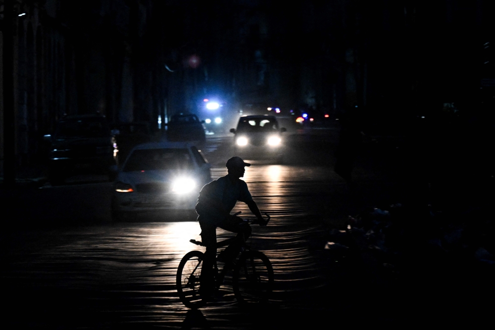 A man rides his bicycle down a street during a blackout in Havana on August 1, 2026. (Photo by Yamil Lage / AFP)
