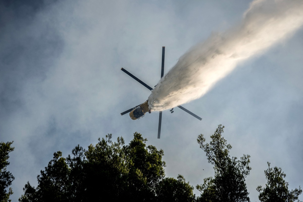 A firefighting helicopter drops water over a wildfire in the area of Porto Germeno, some 70 kilometres (45 miles) northwest of Athens in the region of Viotia, on August 2, 2026. (Photo by Angelos TZORTZINIS / AFP)