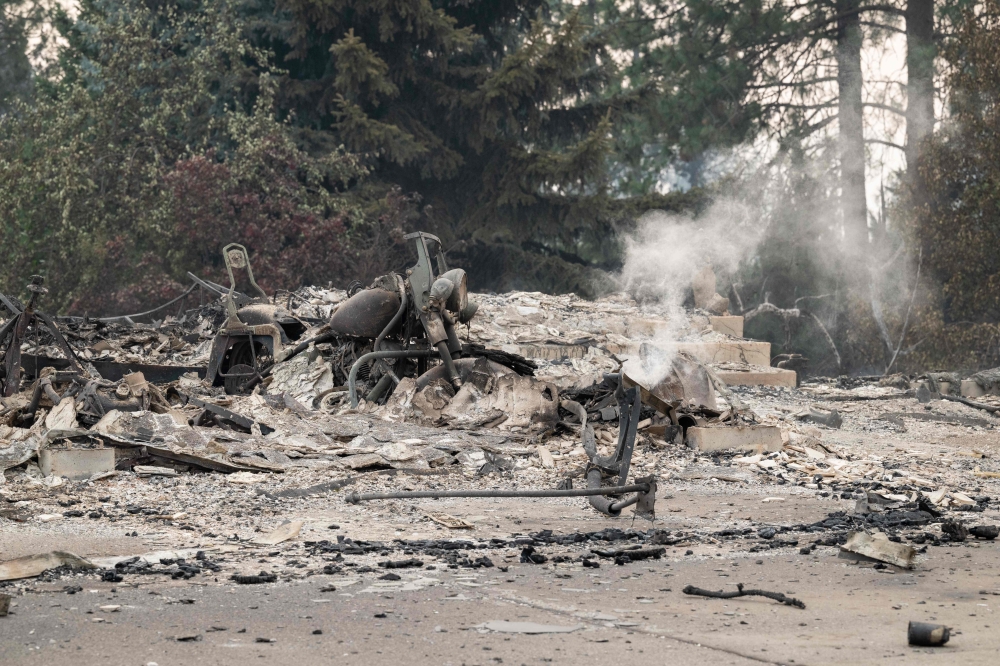 A burned motorcycle sits in the ashes of burned out residential home in the Balboa neighborhood of Spokane, Washington, on August 2, 2026. (Photo by Erick Doxey / AFP)
 