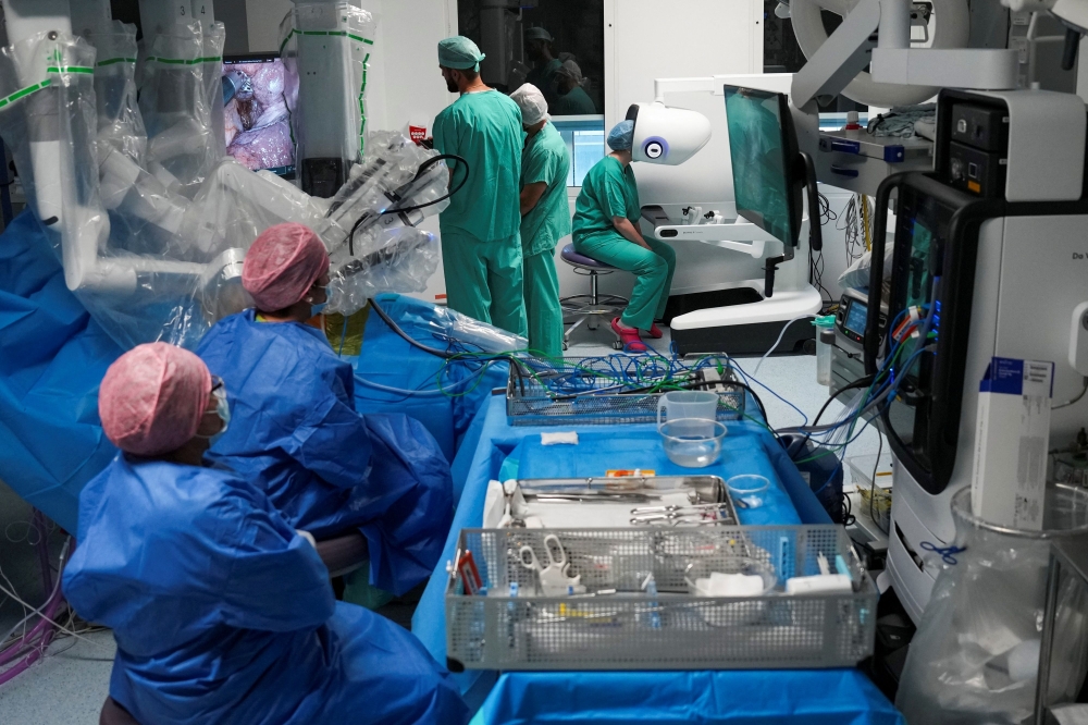 This photo taken on July 3, 2026 shows surgeons and nurses using the new Da Vinci 5 robotic-assisted surgical system while performing surgery, at St Bartholomew's Hospital in London. (Photo by Carlos Jasso / AFP)