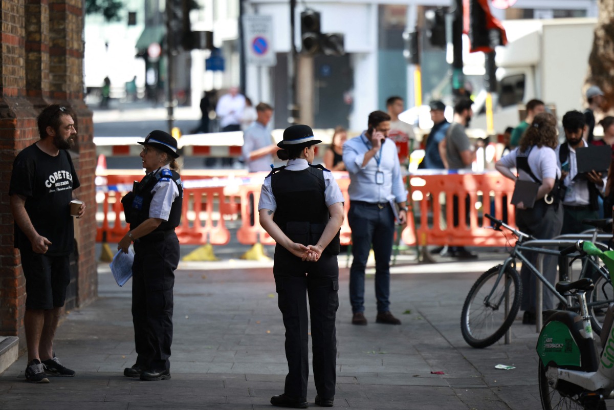 Police community support officers (PCSOs) stand behind cordon tape at Endell road in covent garden, central London on August 5, 2026. Photo by Henry NICHOLLS / AFP