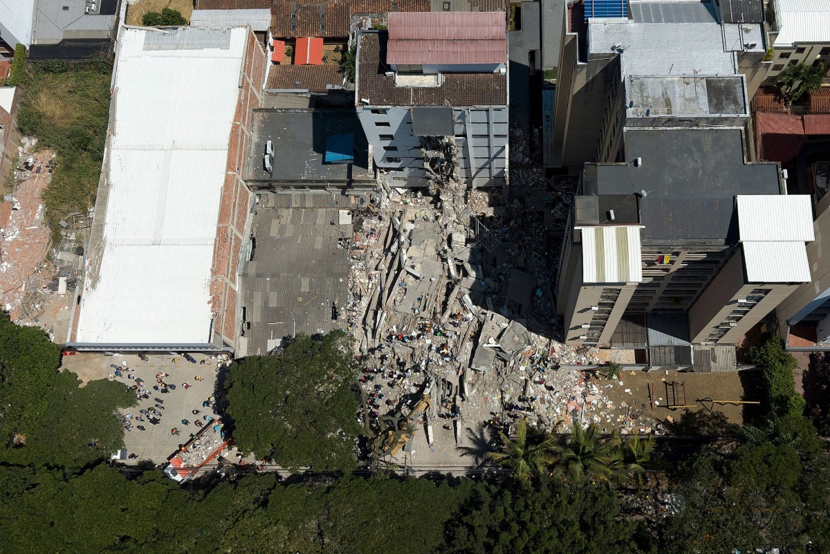 This aerial view shows rescuers searching for survivors amid the rubble of a collapsed building after an earthquake in Cali, Colombia on August 11, 2026. (Photo by JOAQUIN SARMIENTO / AFP)