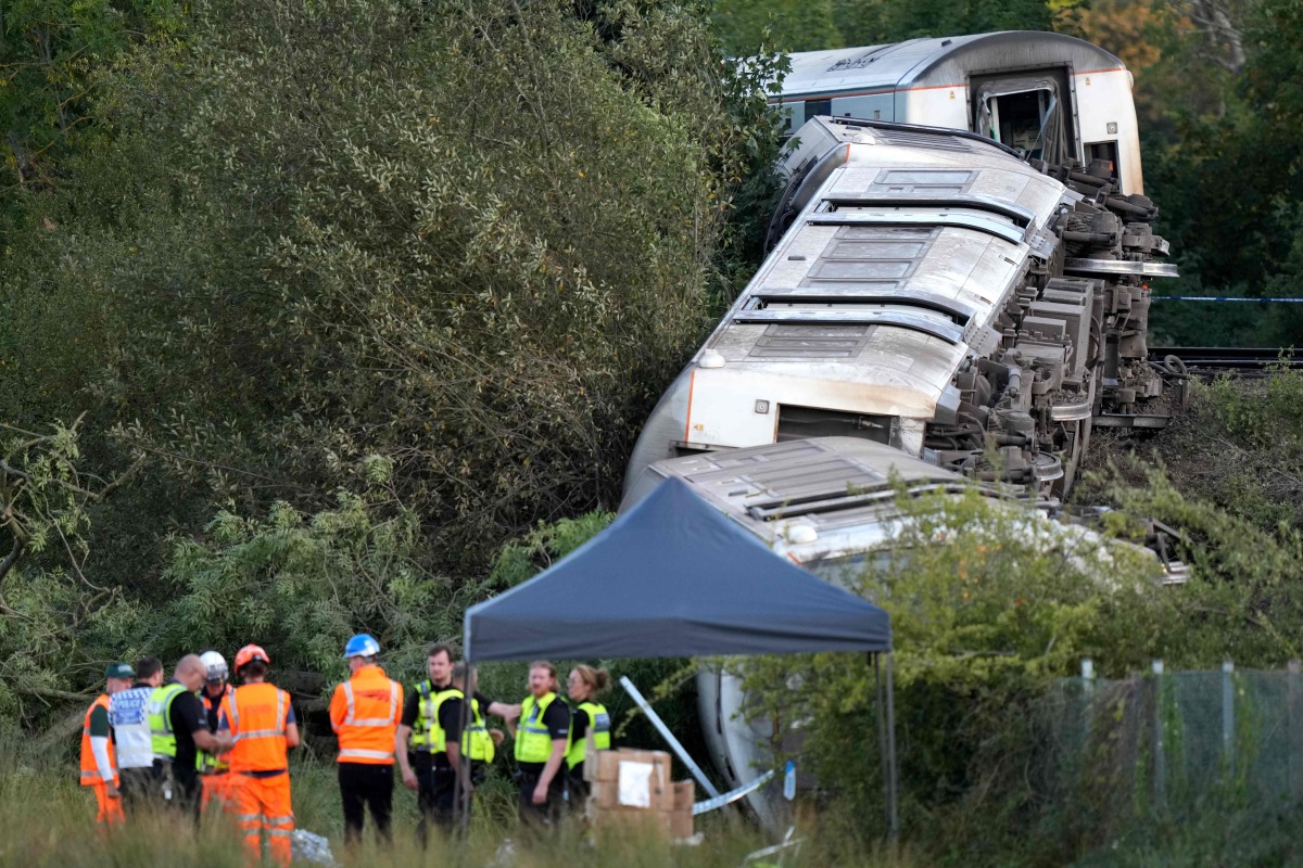 Carriages of a derailed train are pictured on their side, near the town of Lewes, southern England on August 13, 2026. Two people sustained 