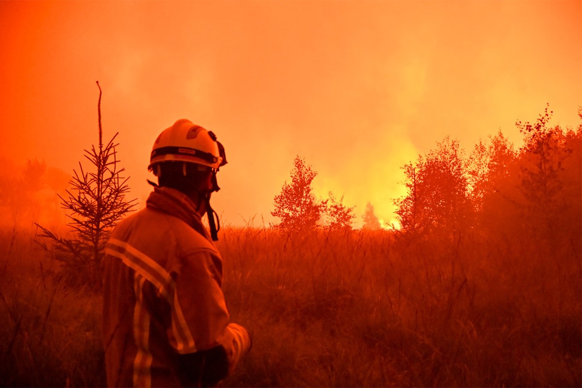 This handout photograph taken on August 15, 2026 and released on August 17, 2026 by VHP shows a firefighter looking at wildfire in the Hautes Fagnes (High Fens) nature reserve. Photo by HANDOUT / VHP / AFP