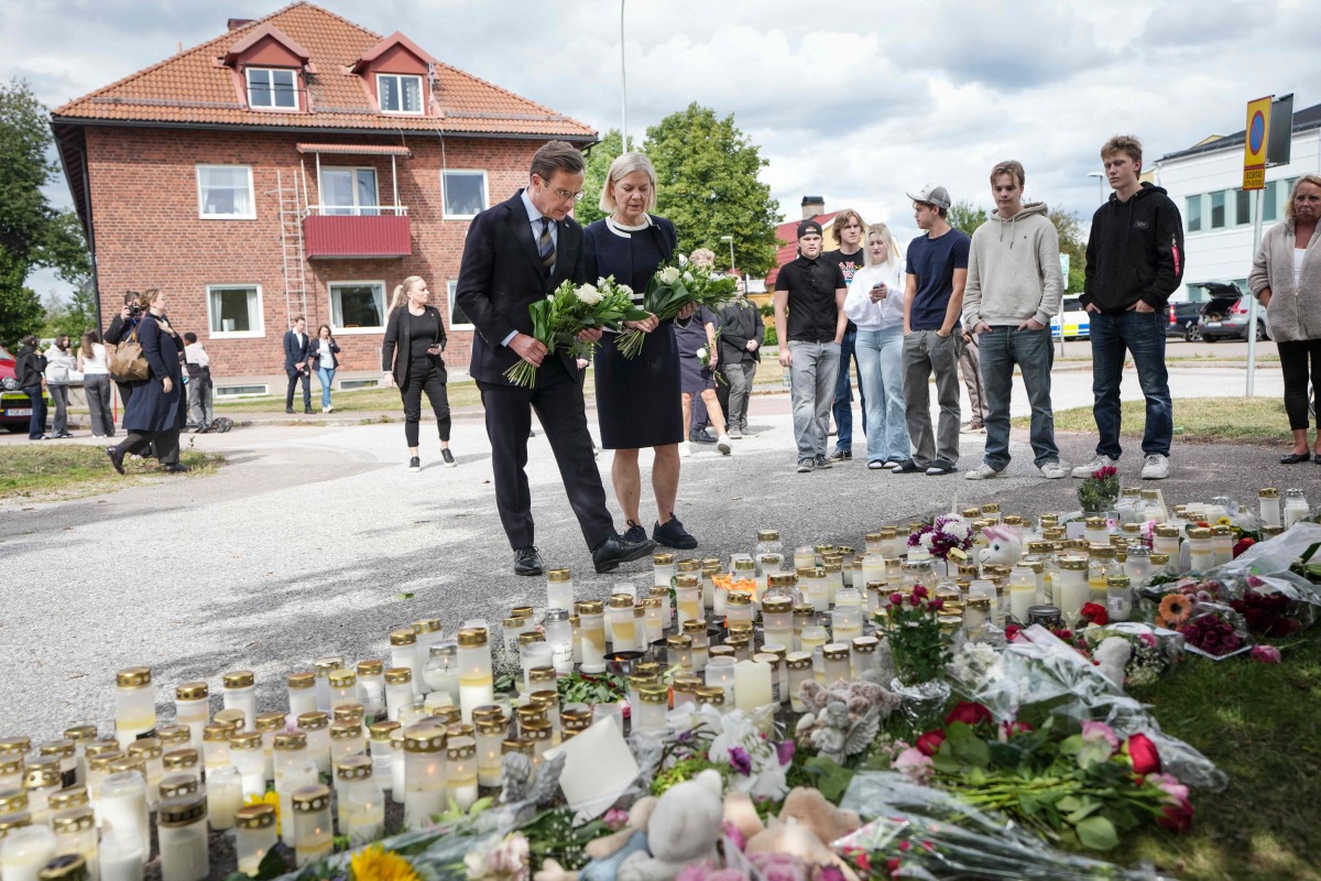 Swedish Prime Minister Ulf Kristersson and Social Democratic Party leader Magdalena Andersson visit the makeshift memorial outside a school in Fagersta, central Sweden, on August 22, 2026, a day after a 17-year-old girl was killed and three other people were injured in a sword attack at the school. Photo by Magnus LEJHALL / TT NEWS AGENCY / AFP