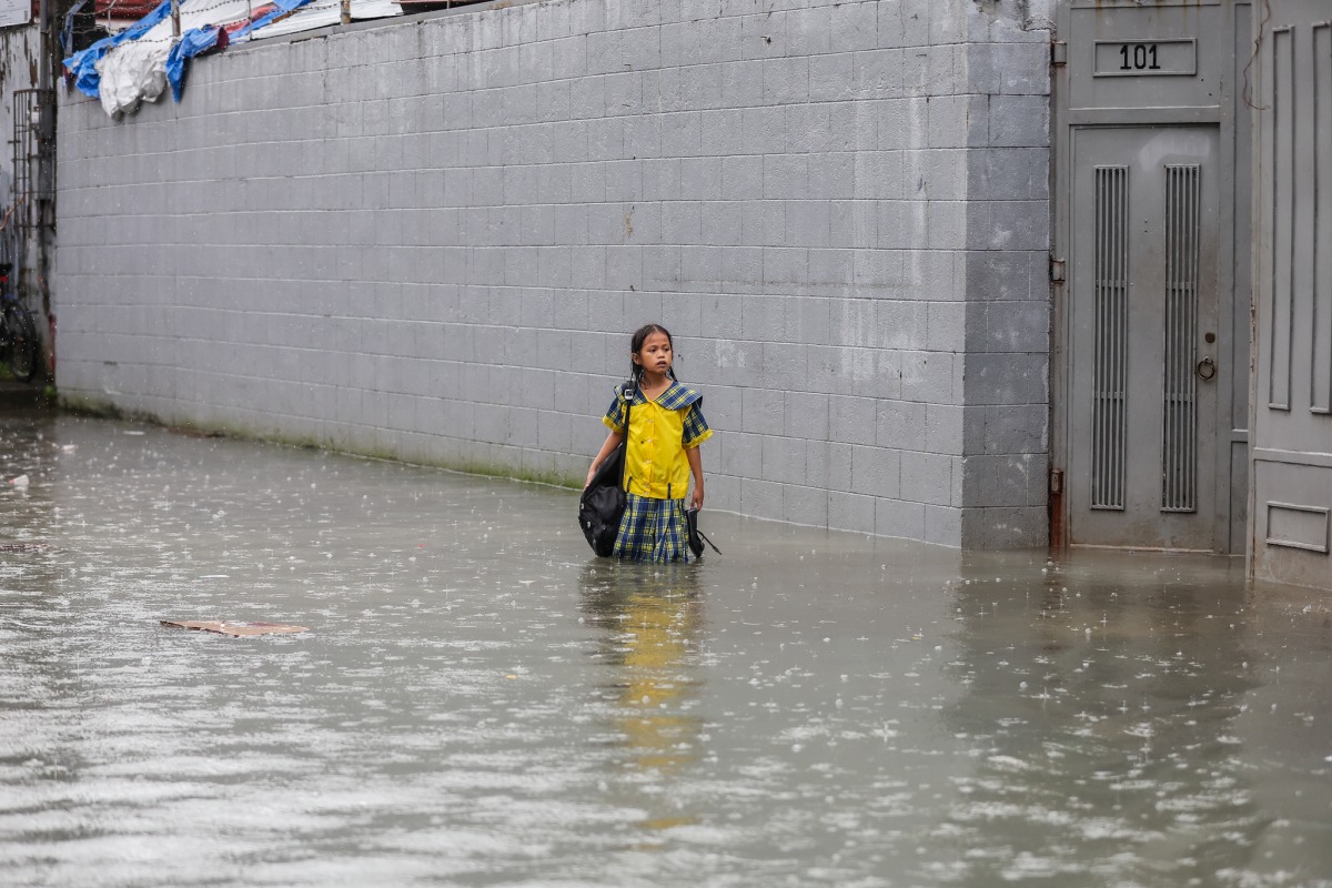 A student stands in floodwater in Quezon City, the Philippines, on Aug. 17, 2026. (Xinhua/Rouelle Umali)