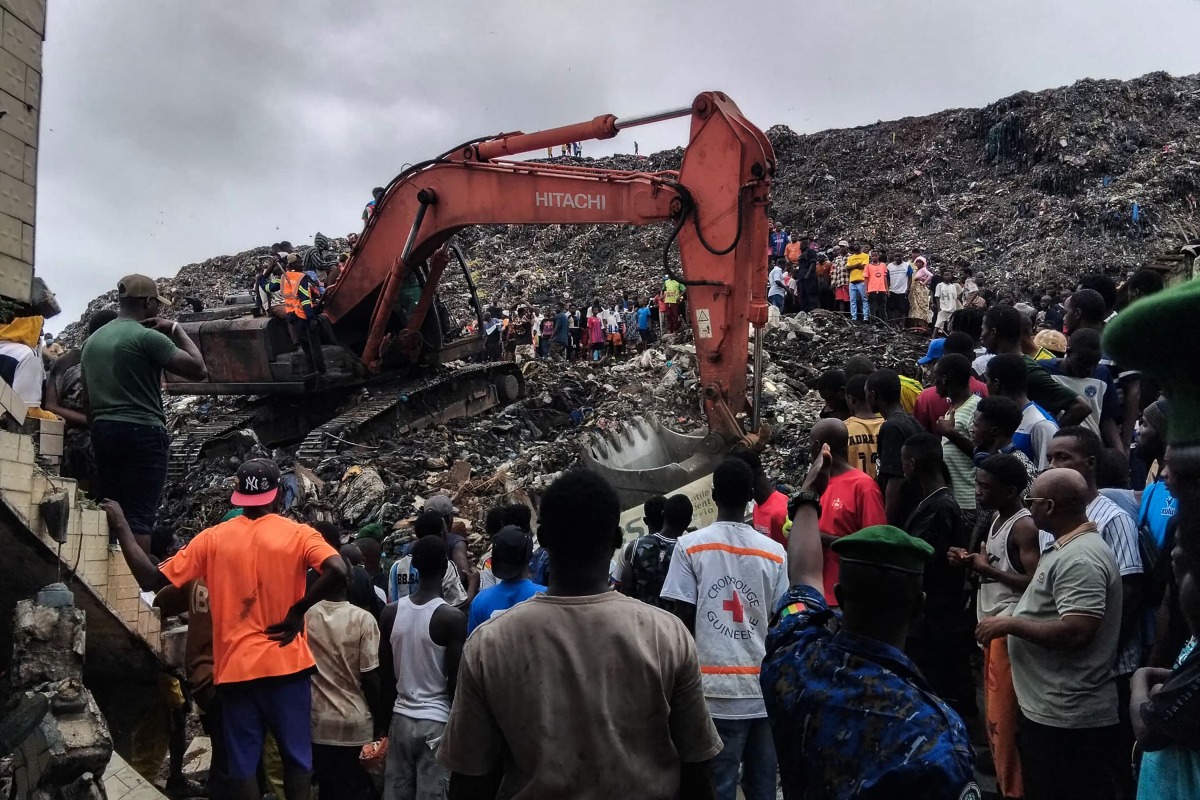 Residents and rescuers use an excavator to search for bodies after a landslide struck the Dar es Salaam dumpsite overnight in Conakry on August 23, 2026.