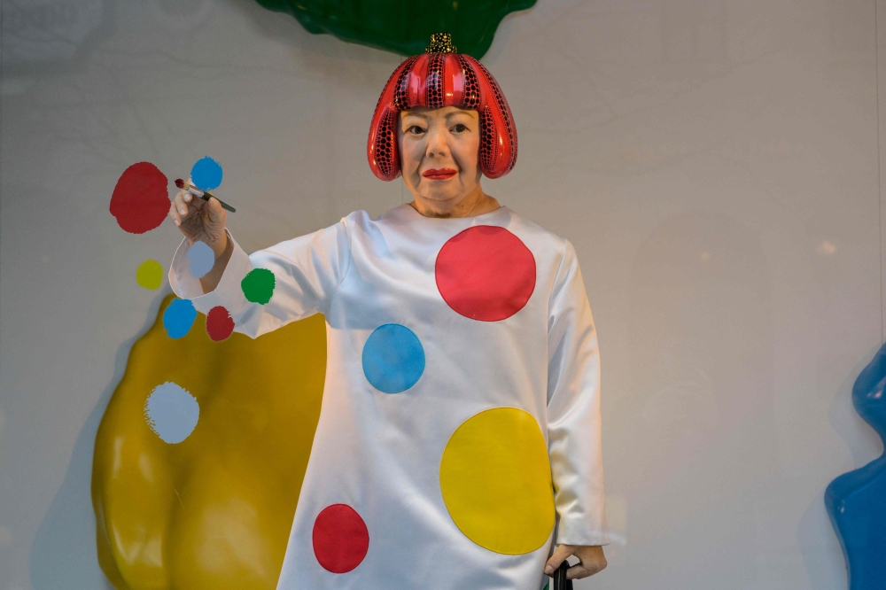(FILE PHOTO) A life-like robot of artist Yayoi Kusama paining a window stands at the Louis Vuitton store on Fifth Avenue in New York City on January 13, 2023. (Photo by ANGELA WEISS / AFP) 