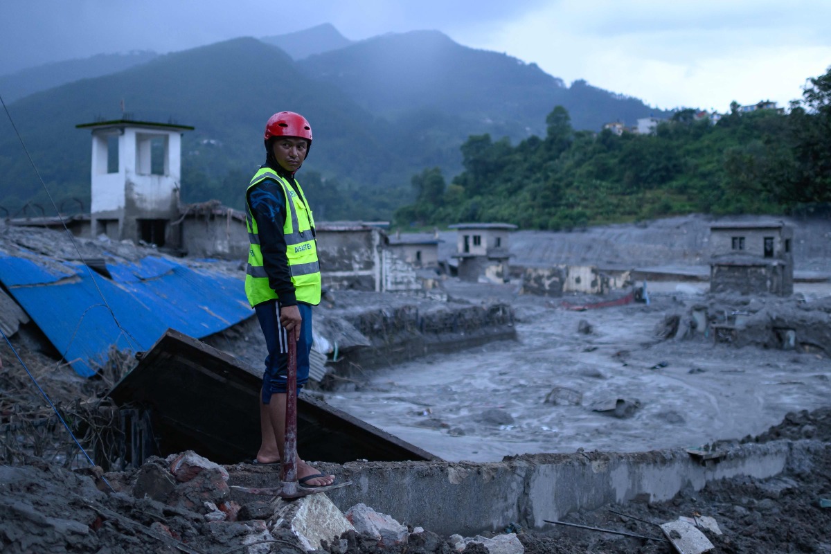 A disaster rescue personnel looks on at the site of damaged buildings in the aftermath of flash floods at Trishuli Bazar in Nepal's Nuwakot district on August 29, 2026. (Photo by MANAN VATSYAYANA / AFP)