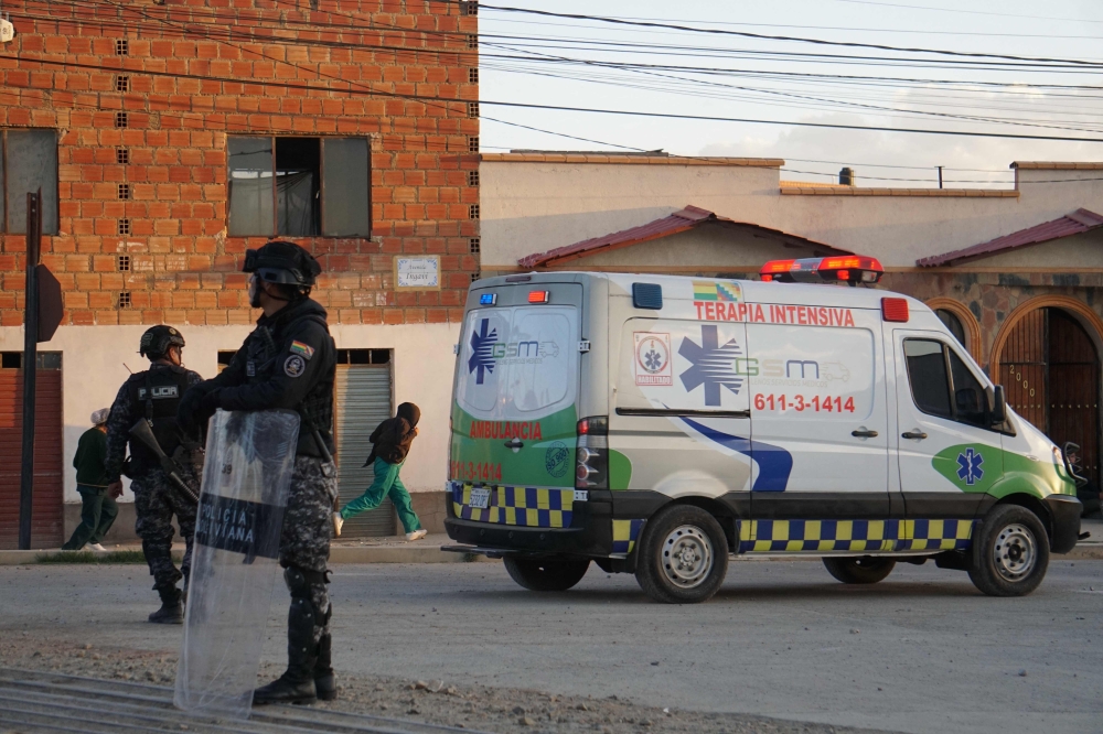 This picture released by APG Noticias shows police officers standing near an ambulance at the site of an explosion at an army barracks in Viacha, Bolivia, on September 4, 2026.  (Photo by APG NOTICIAS / AFP)