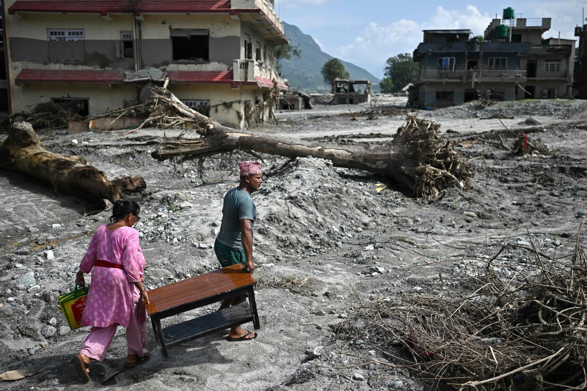 People recover their belongings in the aftermath of flash floods at Devighat in Nepal's Nuwakot district on September 8, 2026. Photo by Pedro PARDO / AFP